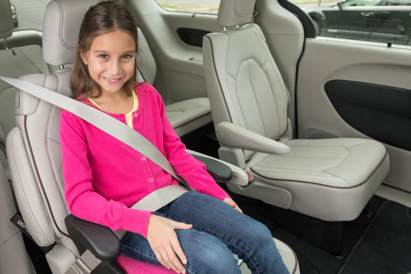 A child sitting on a backless booster seat with the seat belt properly positioned.