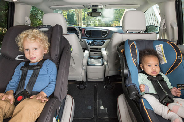 A toddler and an infant, both in rear-facing car seats. 