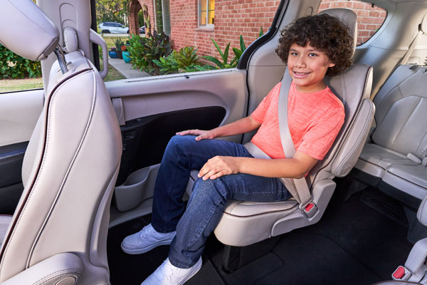 An older child sitting in a vehicle seat with the seat belt properly positioned.